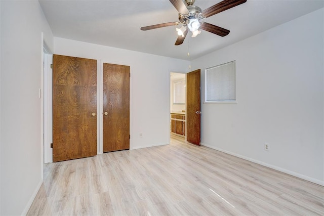 unfurnished bedroom featuring two closets, ensuite bathroom, ceiling fan, and light wood-type flooring