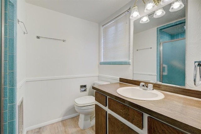 bathroom featuring vanity, hardwood / wood-style flooring, a shower with door, and toilet