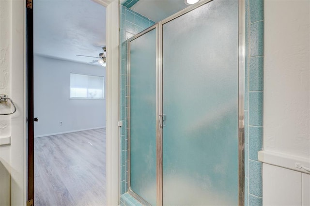 bathroom featuring wood-type flooring, a shower with door, and ceiling fan