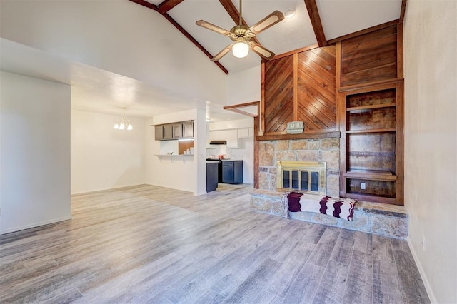 unfurnished living room with beamed ceiling, a fireplace, ceiling fan with notable chandelier, and light wood-type flooring