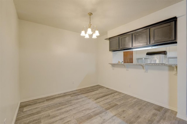 unfurnished dining area featuring a notable chandelier and light wood-type flooring