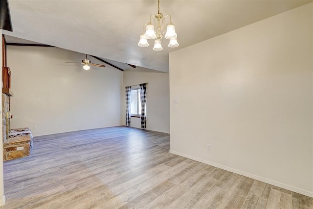 empty room featuring light hardwood / wood-style flooring, ceiling fan with notable chandelier, and vaulted ceiling