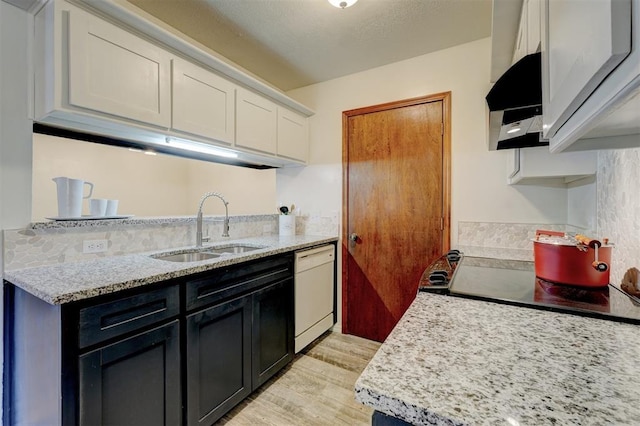 kitchen featuring sink, dishwasher, light stone counters, white cabinets, and light wood-type flooring