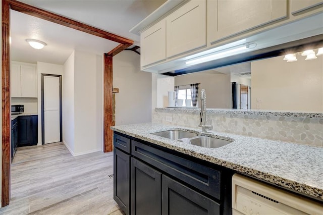 kitchen with sink, white dishwasher, light stone countertops, light hardwood / wood-style floors, and white cabinets