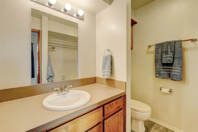 bathroom with vanity, toilet, and hardwood / wood-style floors