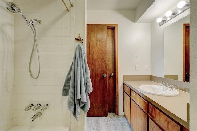 bathroom featuring hardwood / wood-style flooring, tiled shower / bath, and vanity