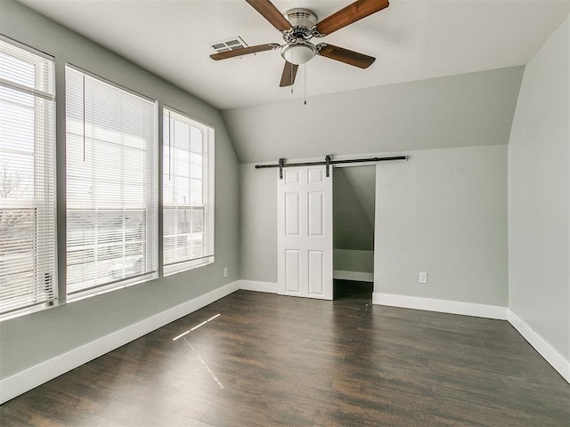 spare room featuring a barn door, dark hardwood / wood-style floors, lofted ceiling, and ceiling fan