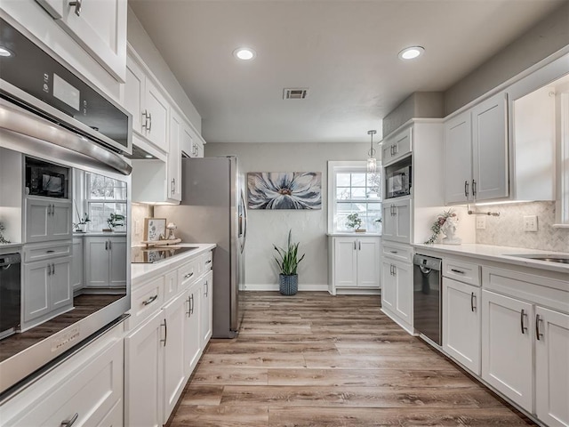 kitchen with black appliances, light hardwood / wood-style floors, and white cabinets