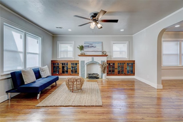 living room with ceiling fan, ornamental molding, and light wood-type flooring