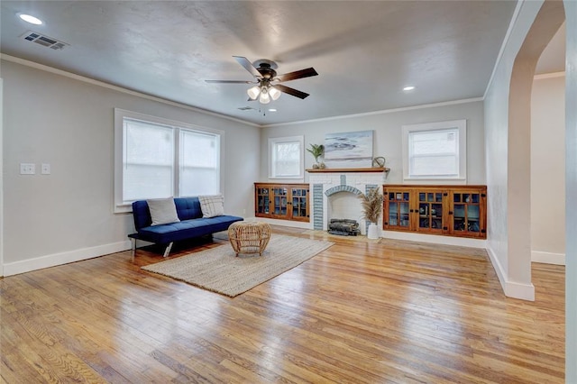 living room with crown molding, a fireplace, light hardwood / wood-style floors, and a wealth of natural light