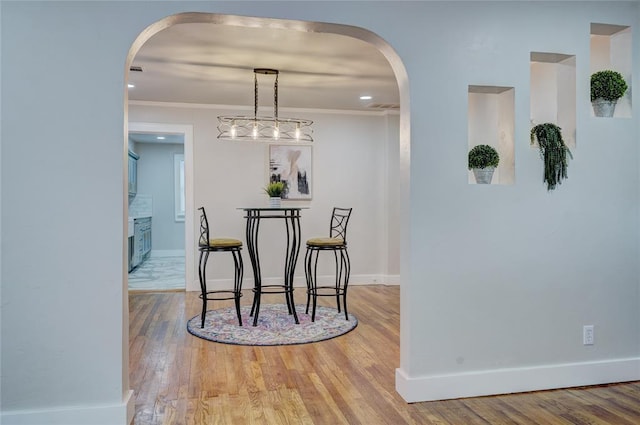 dining space featuring ornamental molding and light wood-type flooring