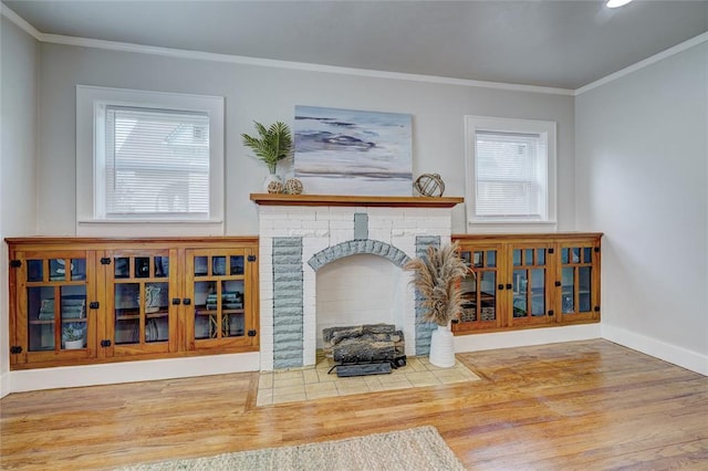 living room with a brick fireplace, crown molding, and hardwood / wood-style floors