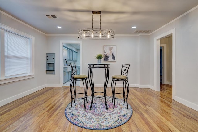 dining space featuring ornamental molding and light hardwood / wood-style floors