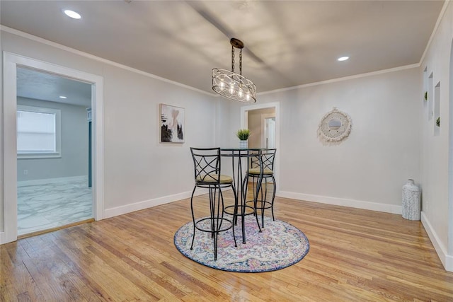 dining area with ornamental molding and light wood-type flooring