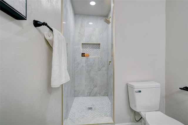 bathroom featuring a tile shower and toilet