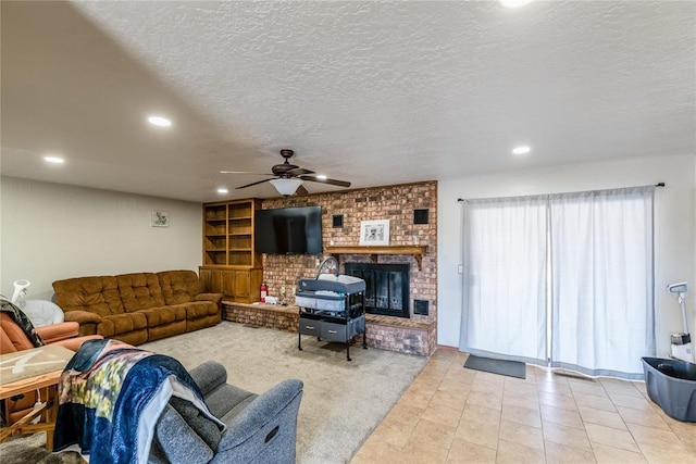 living room featuring a brick fireplace, light tile patterned floors, a textured ceiling, and ceiling fan