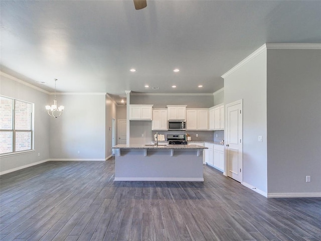 kitchen featuring dark wood-type flooring, a breakfast bar, white cabinetry, appliances with stainless steel finishes, and a kitchen island with sink