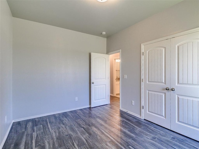 unfurnished bedroom with dark wood-type flooring and a closet