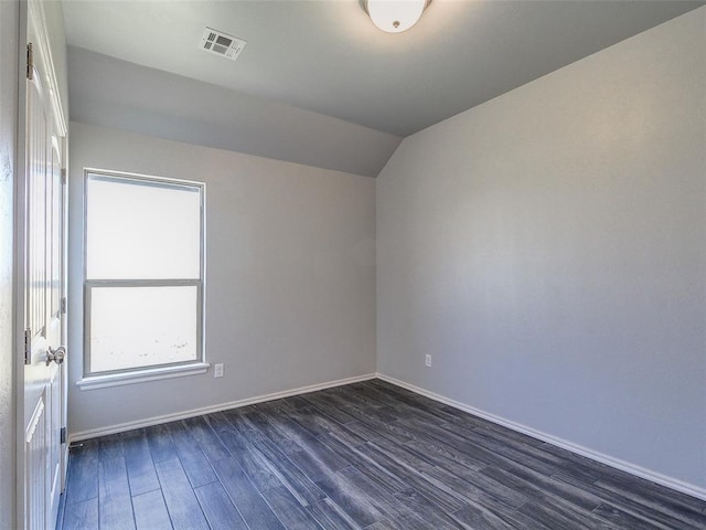 empty room featuring vaulted ceiling and dark hardwood / wood-style floors