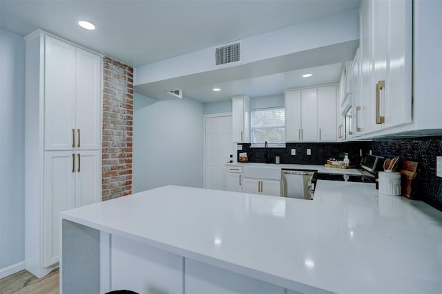 kitchen featuring stainless steel dishwasher, white cabinets, and kitchen peninsula