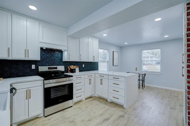 kitchen with electric stove, kitchen peninsula, tasteful backsplash, and white cabinets