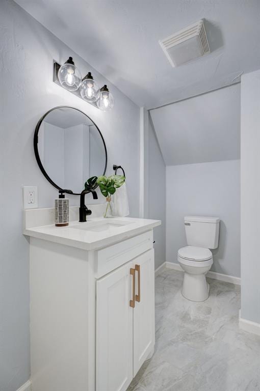 bathroom featuring lofted ceiling, vanity, and toilet