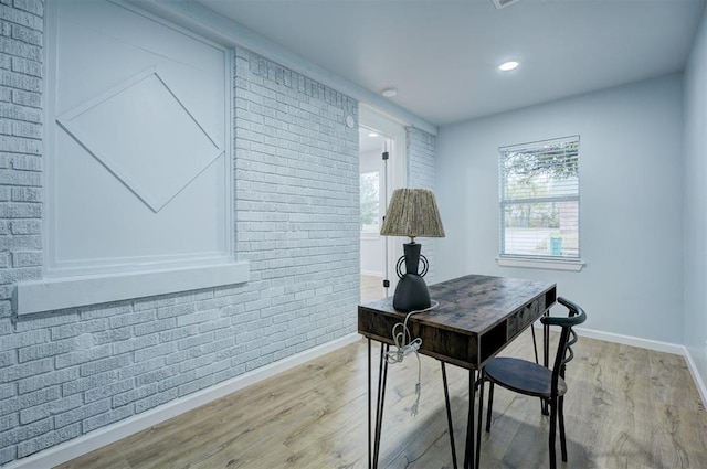 home office featuring brick wall and light wood-type flooring