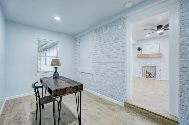 office area featuring hardwood / wood-style floors, ceiling fan, and brick wall