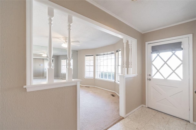 carpeted entrance foyer featuring ceiling fan, ornamental molding, and a textured ceiling