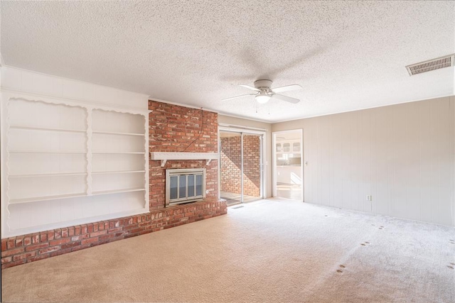 unfurnished living room with a brick fireplace, a textured ceiling, built in features, ceiling fan, and carpet