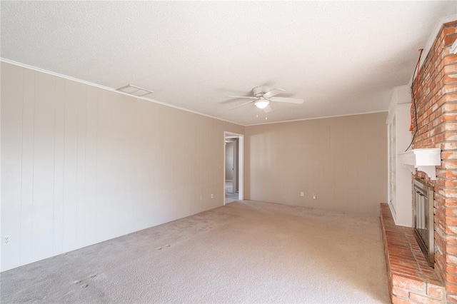 unfurnished living room with a brick fireplace, ornamental molding, ceiling fan, and carpet