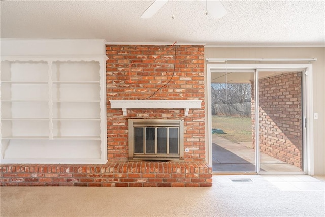 unfurnished living room featuring ceiling fan, carpet, a fireplace, ornamental molding, and a textured ceiling