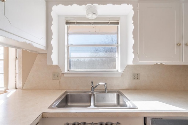 kitchen featuring white cabinetry, dishwashing machine, and sink