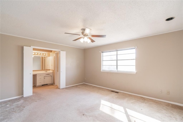 unfurnished bedroom featuring crown molding, connected bathroom, light colored carpet, and a textured ceiling