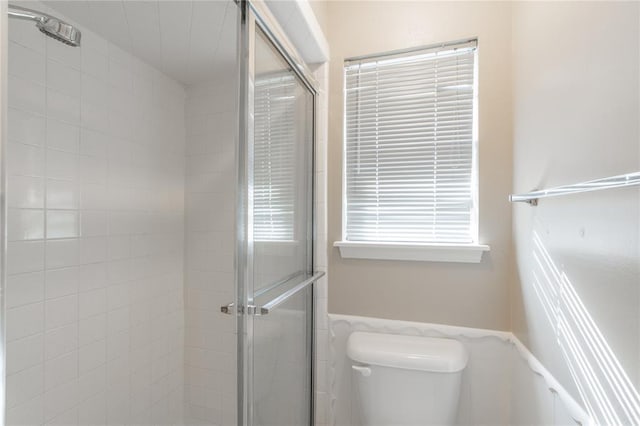 bathroom with a shower with shower door and toilet