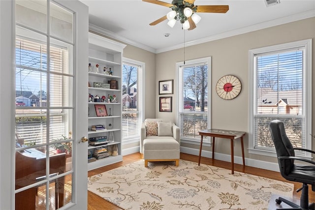 living area featuring crown molding, a wealth of natural light, ceiling fan, and light hardwood / wood-style floors