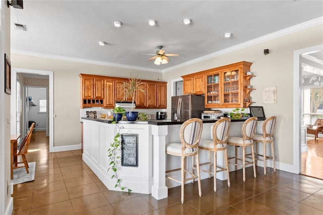 kitchen featuring ornamental molding, stainless steel fridge with ice dispenser, a breakfast bar area, and kitchen peninsula