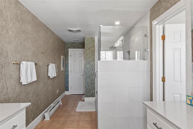 bathroom with a tile shower, vanity, tile patterned floors, and baseboard heating