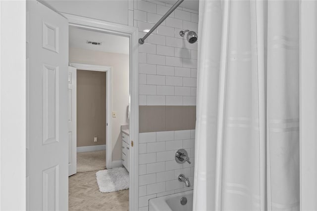 bathroom with parquet floors, vanity, and shower / tub combo