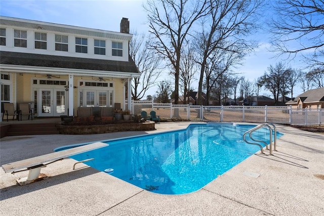 view of pool with french doors, ceiling fan, a diving board, and a patio