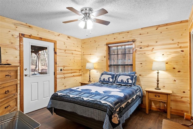 bedroom with dark hardwood / wood-style flooring, ceiling fan, wooden walls, and a textured ceiling