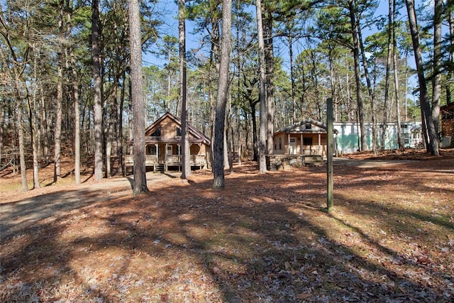 view of front of property featuring covered porch and a wooded view