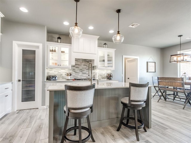 kitchen with light wood-style floors, tasteful backsplash, visible vents, and light countertops