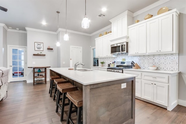 kitchen with pendant lighting, appliances with stainless steel finishes, sink, and a center island with sink