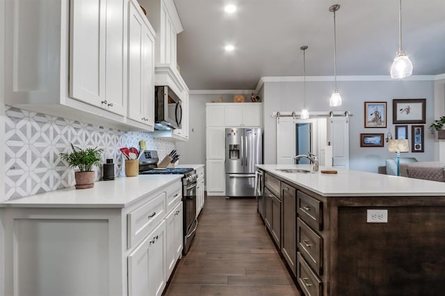 kitchen featuring sink, white cabinetry, decorative light fixtures, appliances with stainless steel finishes, and a barn door