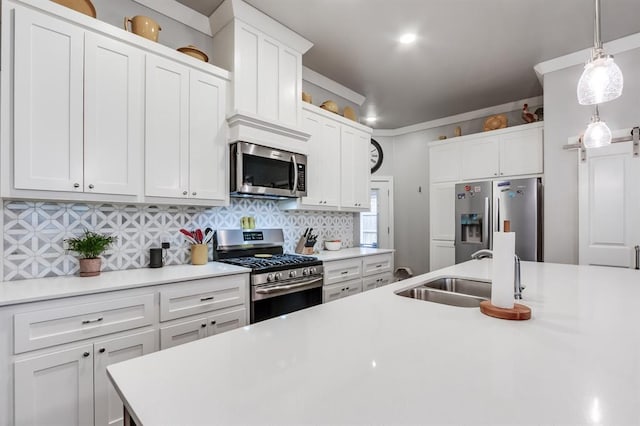 kitchen featuring pendant lighting, sink, white cabinets, backsplash, and stainless steel appliances