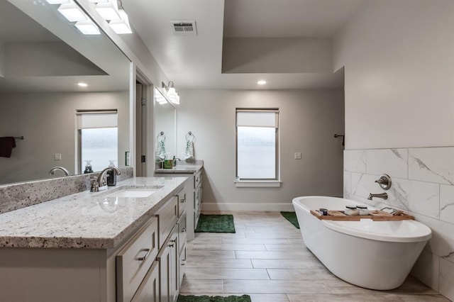 bathroom featuring vanity, a tub, and tile walls