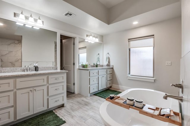 bathroom with vanity, a tub to relax in, and a wealth of natural light