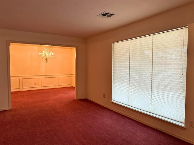 empty room featuring a chandelier and carpet flooring