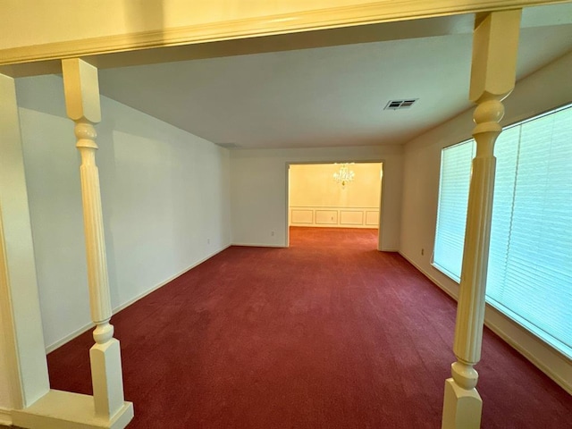 carpeted empty room with a notable chandelier